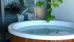 A modern bathroom with a wooden bathtub, a small wooden stool, and a potted plant. - Full Stylish 2BR apartment in heart of town by Happy Address (Playa del Carmen)
