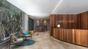 A modern reception area with a wooden wall, a reception desk, and a seating area with a table and chairs. - New and modern 2BR downtown apartment by Happy Address (Playa del Carmen)