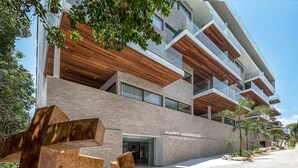 A modern building with a sign reading "HAPPY ADDRESS Vacation Rental Bungalow". - New and modern 2BR downtown apartment by Happy Address (Playa del Carmen)