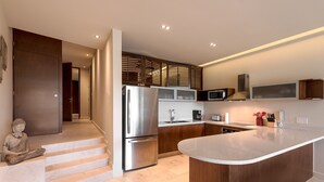 Una cocina moderna con una isla central, electrodomésticos de acero inoxidable, armarios de madera y un microondas integrado.