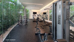 Ett modernt gym med olika typer av träningsutrustning, stora fönster och inomhusväxter.