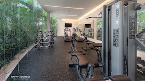 Une salle de sport moderne dotée de divers équipements d’exercice, de grandes fenêtres et de plantes d’intérieur.