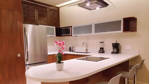 A modern kitchen with a central island, stainless steel appliances, a microwave, and a coffee maker. - Cozy 1 BR apartment steps away from the Beach by Happy Address (Playa del Carmen)