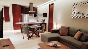 A modern living room with a sofa, coffee table, and dining area with chairs and a table. - Cozy 1 BR apartment steps away from the Beach by Happy Address (Playa del Carmen)