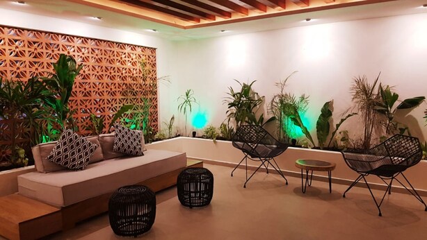 A modern lounge area with a sofa, two black chairs, and a small table. - Cute 1 BR in amazing location by Happy Address (Playa del Carmen)