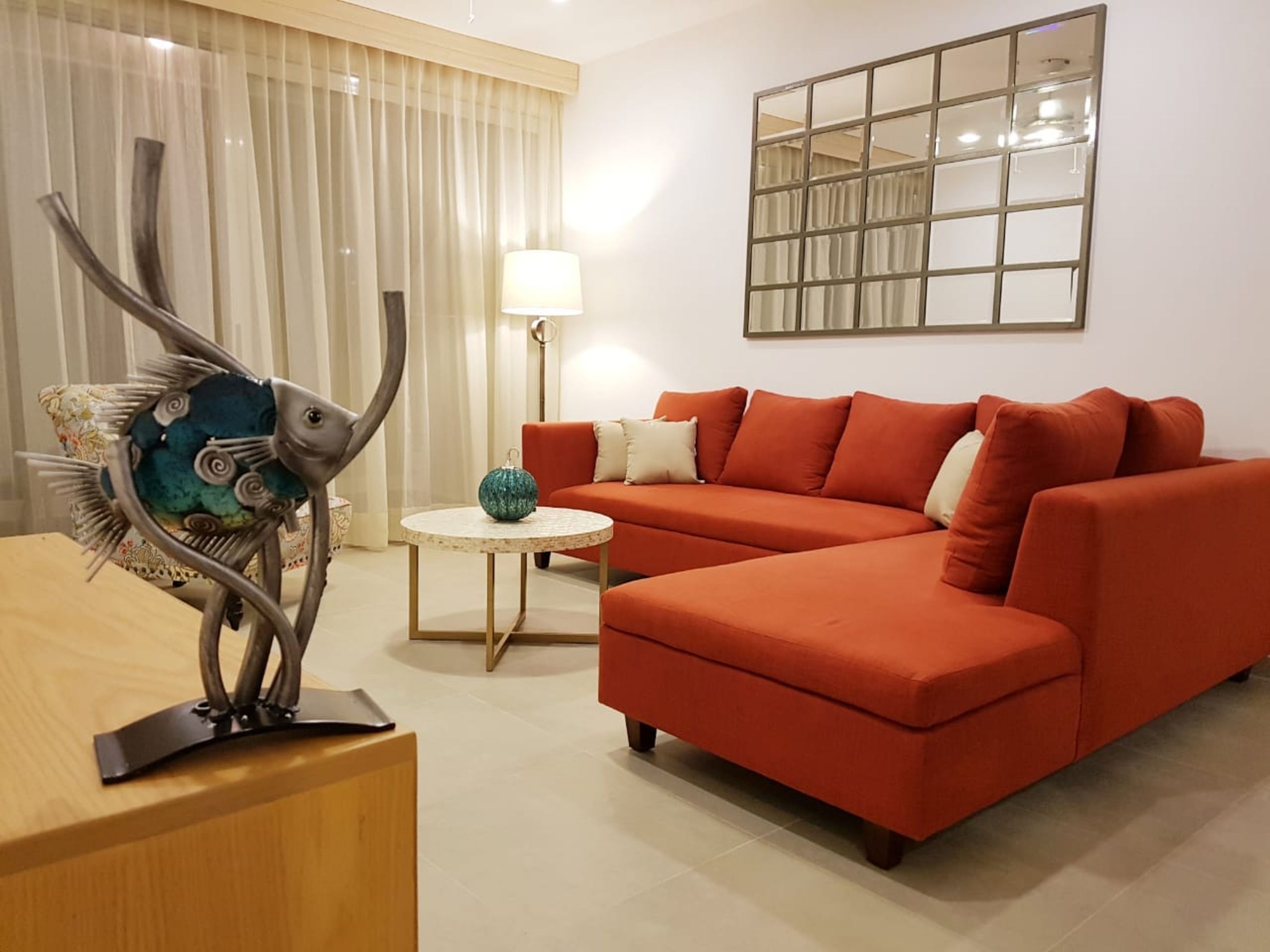 Una sala de estar con un sofá rojo, una mesa de centro redonda y una escultura decorativa de un pez.