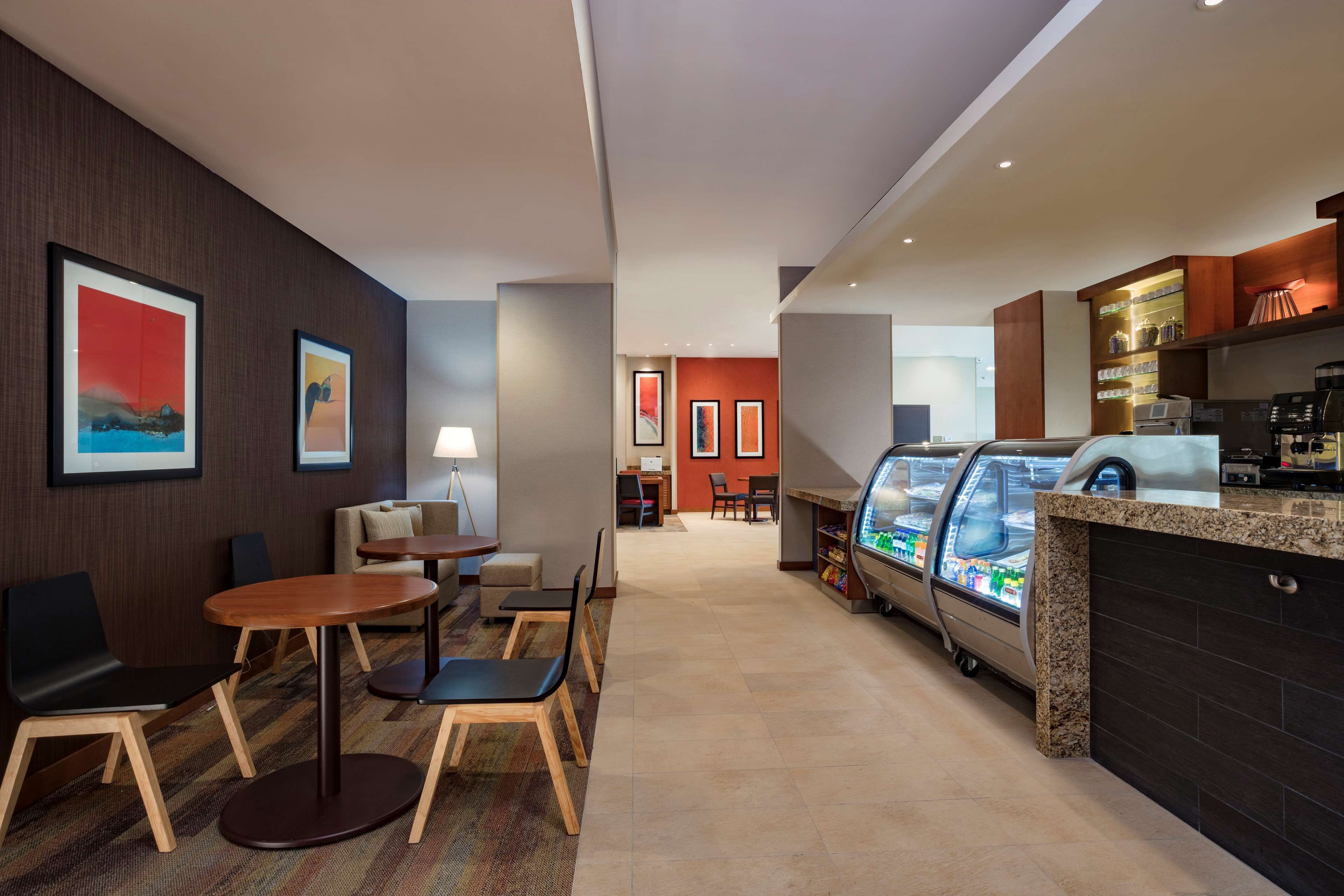 Un hall d’hôtel comprenant des espaces de détente, un bar à café et un présentoir réfrigéré.