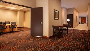 Um saguão de hotel com uma sala de conferências, uma área de estar e uma porta que dá para outro cômodo.