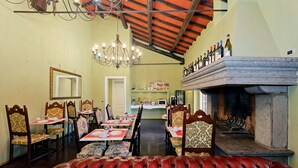 Un comedor con chimenea, sillas de madera y una araña.