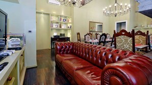 Una sala de estar con un sofá de cuero rojo, una araña y una estantería con diversos objetos.