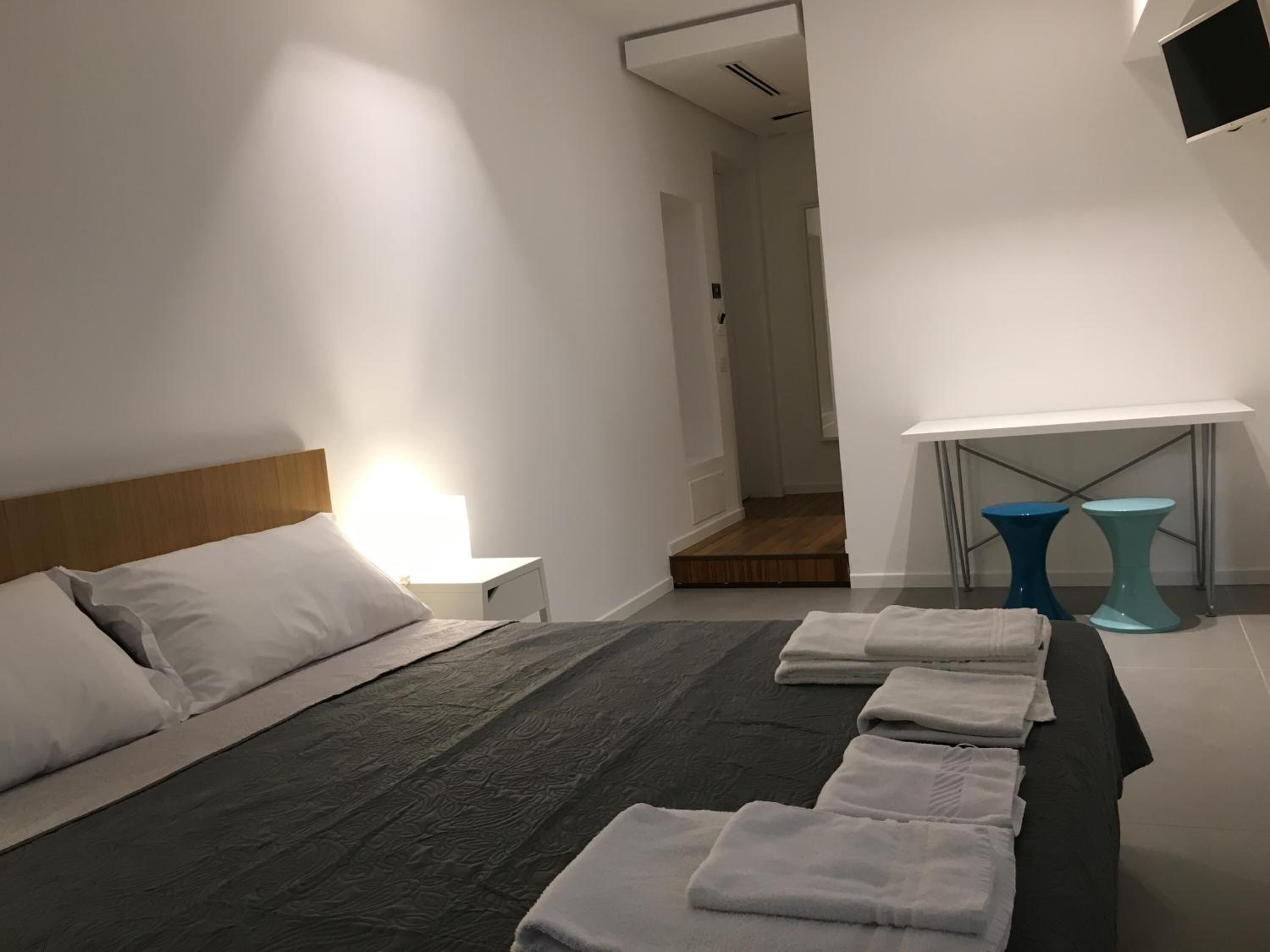 A hotel room with a bed, a nightstand, a lamp, and a TV.