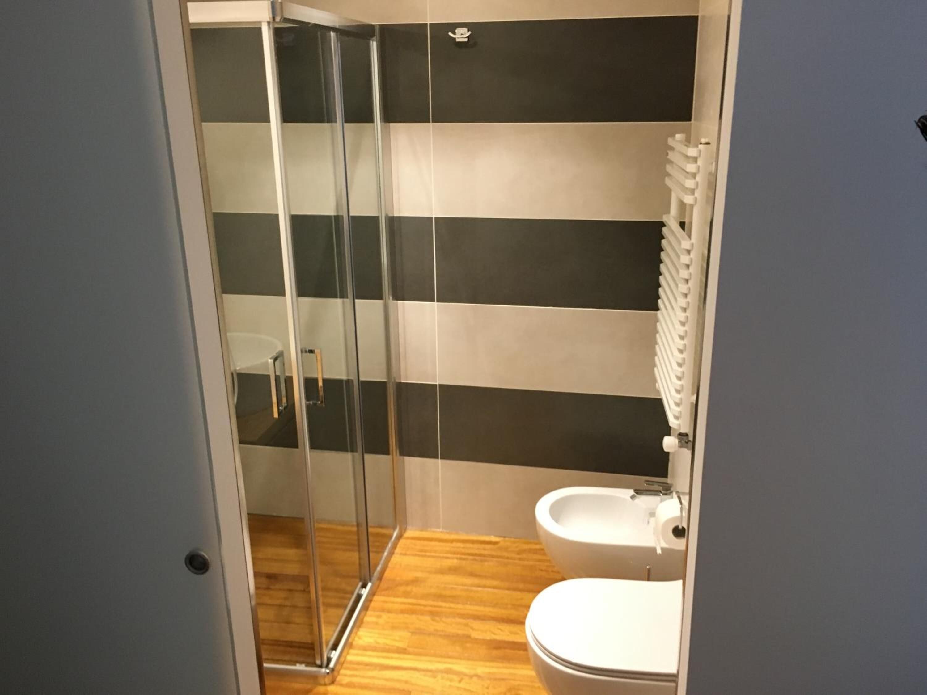Un baño con cabina de ducha de vidrio, un lavamanos blanco y un inodoro.