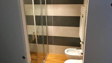 Un baño con cabina de ducha de vidrio, un lavamanos blanco y un inodoro.
