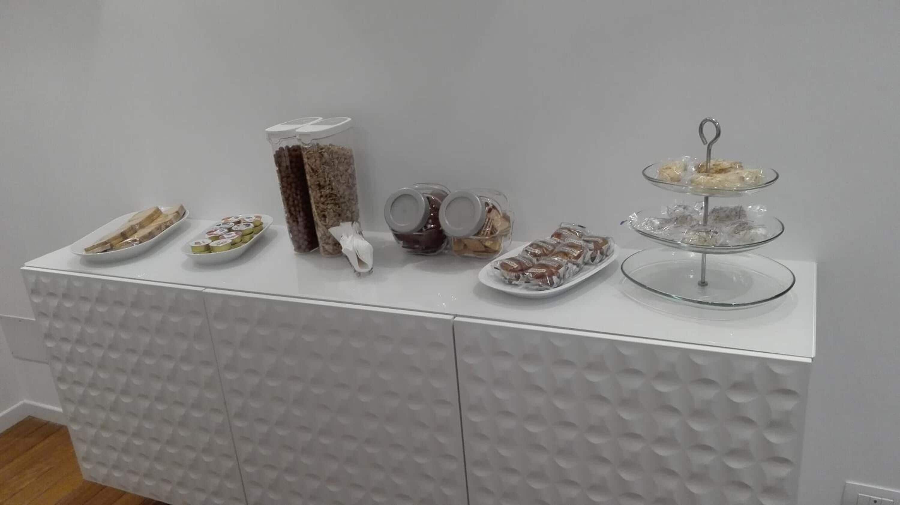 A white buffet table with various food items and containers.