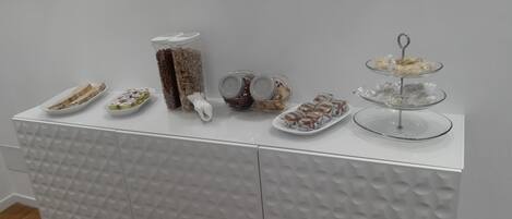 A white buffet table with various food items and containers.