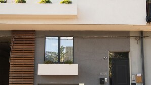 A modern two-story building with a flat roof, a black front door, and a no parking sign. - B&B Brezza di Mare (Aci Castello)