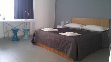 Quarto moderno com uma cama grande, cabeceira de madeira e janela com cortinas.