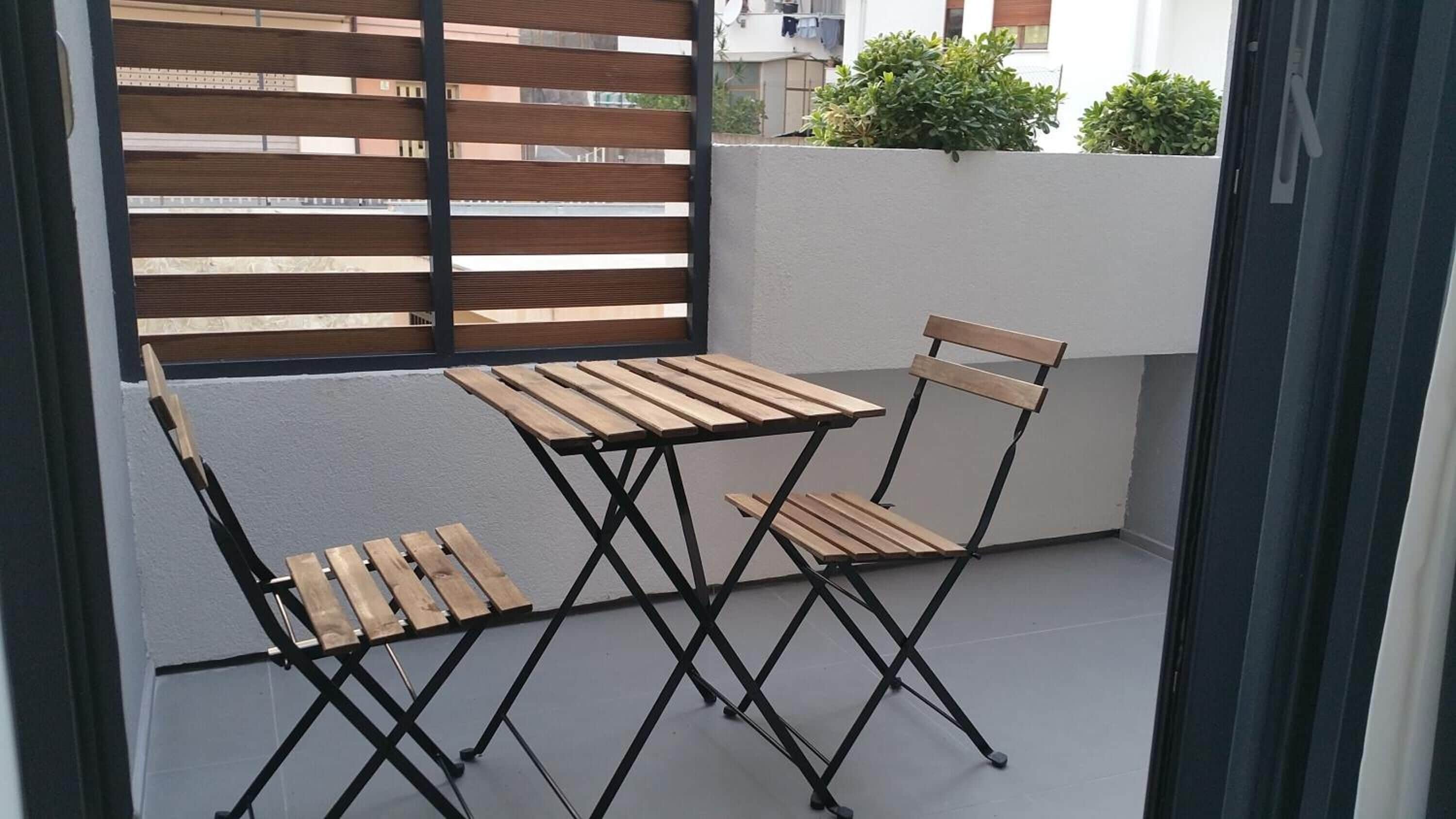 A small outdoor balcony with a wooden table and two chairs.