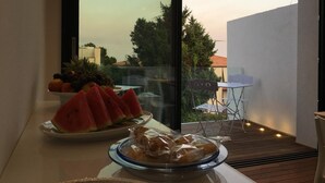 A dining area with a table set for two, featuring a bowl of fruit and a plate of sliced watermelon. - B&B Brezza di Mare (Aci Castello)