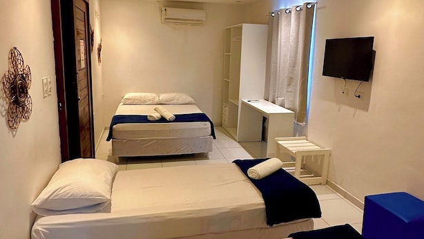 A hotel room with two beds, a TV, and a desk. - Pousada Paranambuca (Ipojuca)