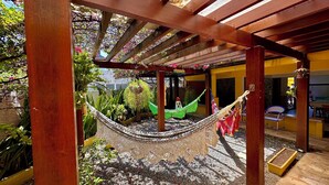 A wooden pergola with a hammock and potted plants. - Pousada Paranambuca (Ipojuca)
