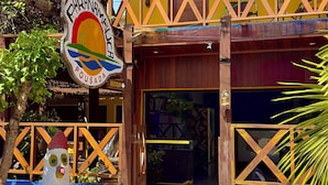 A building with a wooden balcony, a sign reading "Pousada", and a decorative figure in front. - Pousada Paranambuca (Ipojuca)