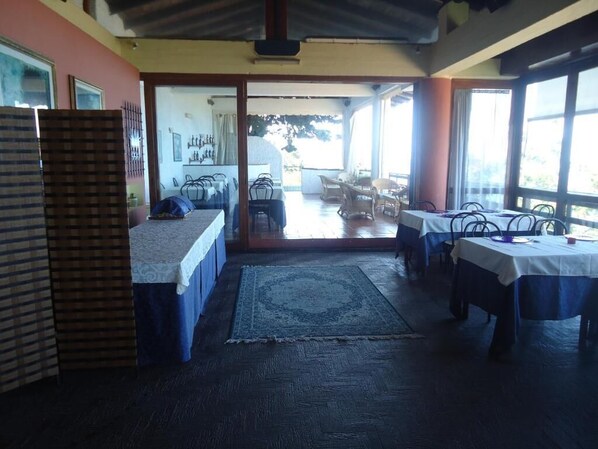 A room with a bed, a table, and chairs. There is a window and a door leading to another room. - Hotel i Normanni (Praia a Mare)