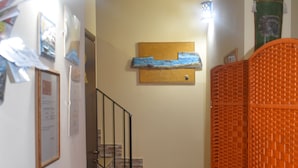 A staircase with a brick wall and a wooden handrail, leading to a landing with a blue and white artwork.