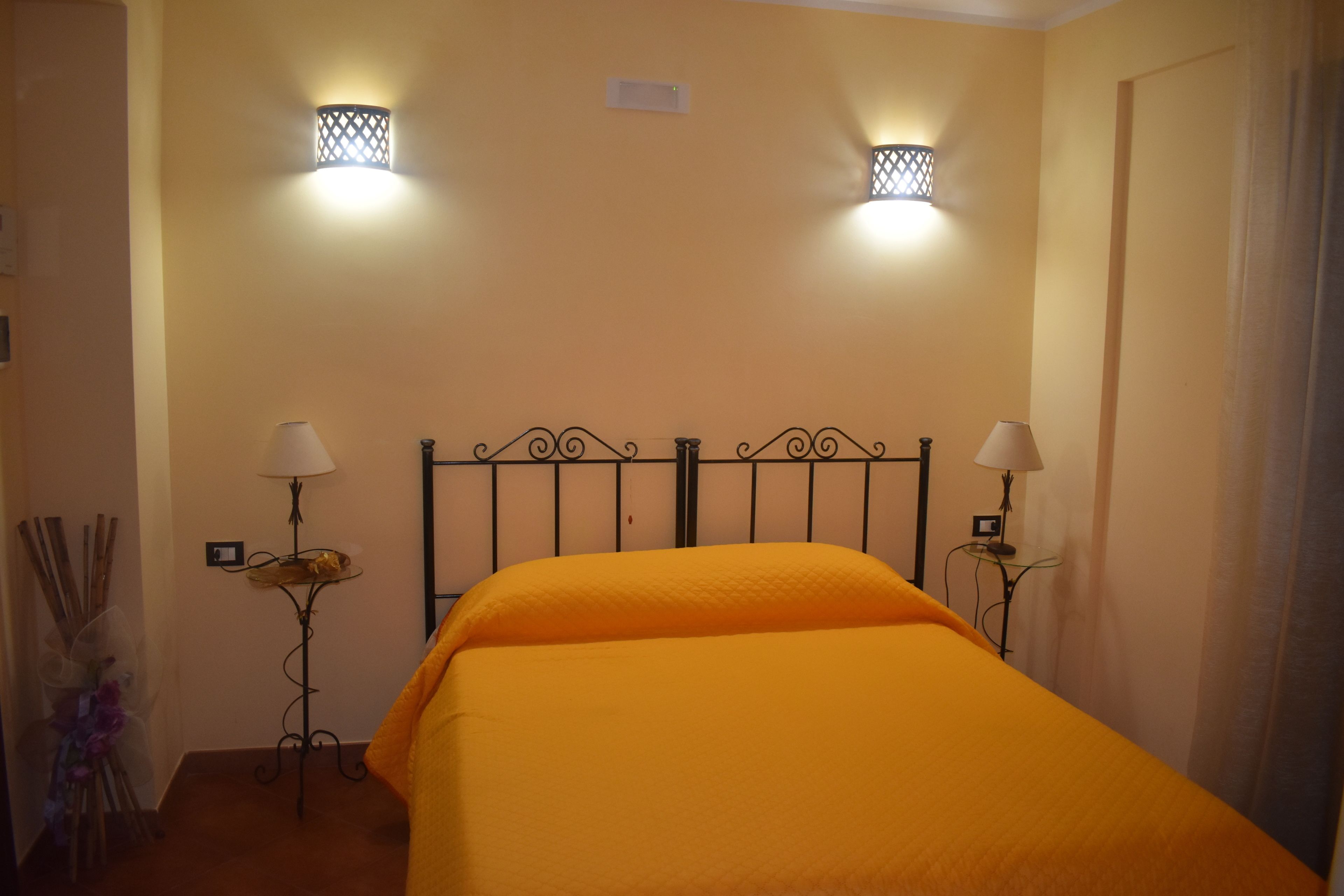 Una habitación con una cama, dos lámparas de pared y una mesita con lámpara.
