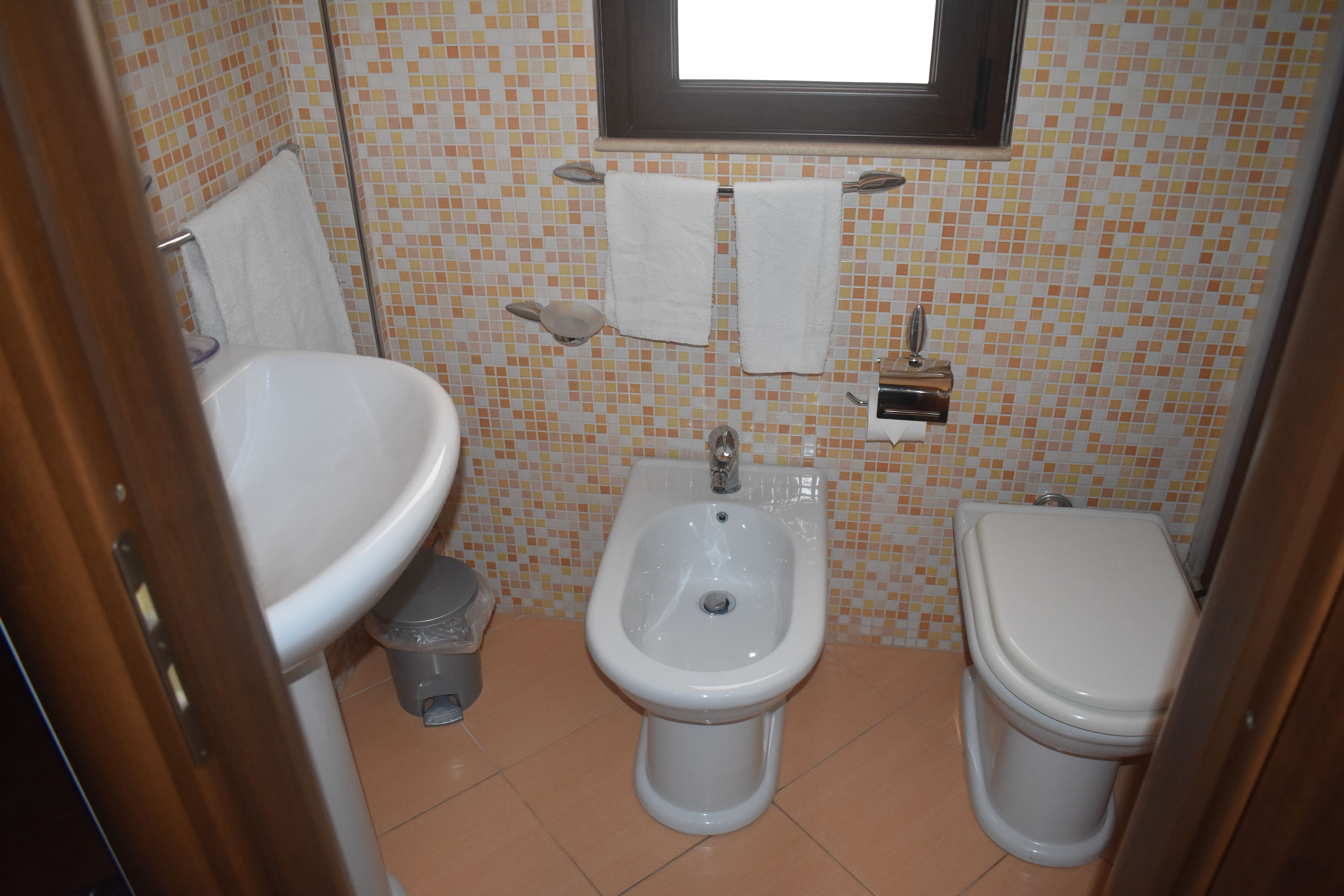 A small bathroom with a sink, bidet, and toilet.