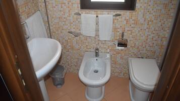 A small bathroom with a sink, bidet, and toilet.