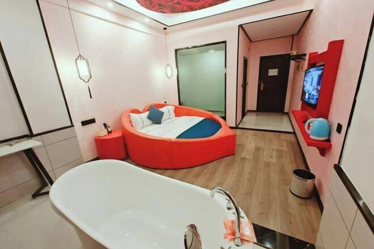A modern bathroom with a bathtub, a circular seating area, and a television.