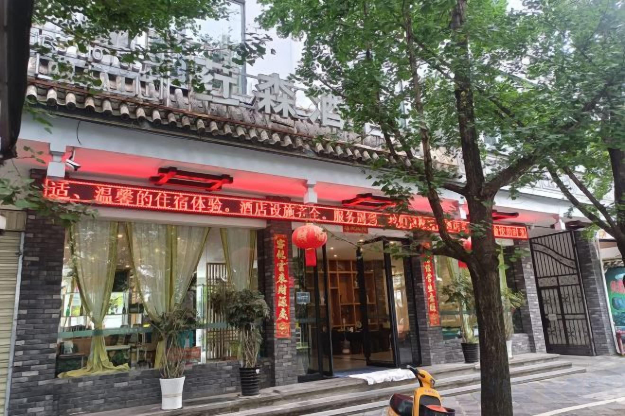 Un bâtiment traditionnel chinois, doté d’un auvent rouge, de grandes fenêtres et de plantes en pot.