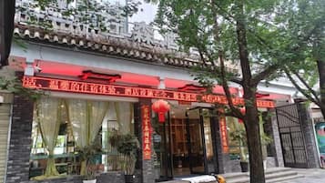 Un edificio tradicional chino con toldo rojo, ventanas amplias y plantas en macetas.