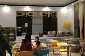 A dining area with tables and chairs, a decorative wall, and a window with curtains. - Hongsen Business Hotel (Tengchong)