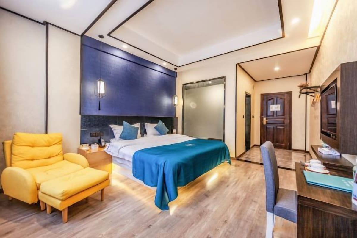A bedroom with a bed, a desk, a chair, and a wardrobe.
