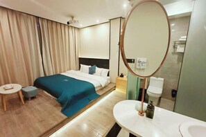 A hotel room with a bed, bedside table, and a bathroom with a mirror and sink.