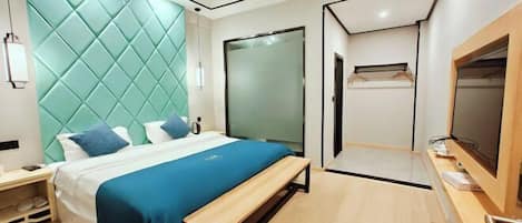 A modern hotel room with a bed, bench, and a wardrobe.