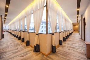 A hotel corridor with a row of rooms, large windows with curtains, and a wooden floor. - Hongsen Business Hotel (Tengchong)