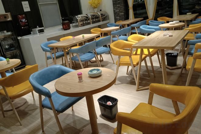 Un espace repas avec des tables et des chaises rondes, une poubelle et un comptoir avec une machine à café.