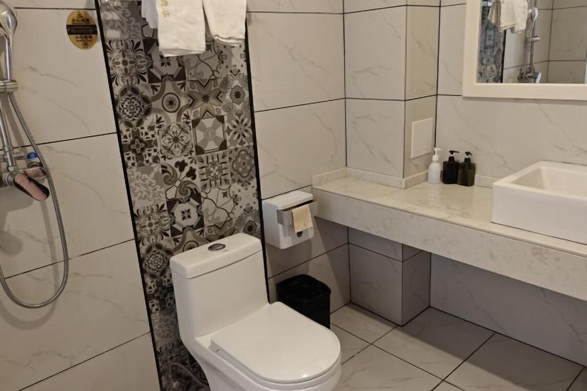 A bathroom with a toilet, a shower, a sink, and a mirror.