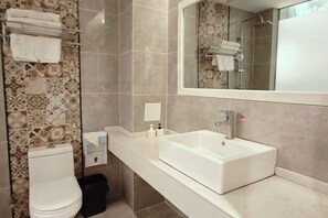 A bathroom with a toilet, a sink, and a large mirror. - Hongsen Business Hotel (Tengchong)