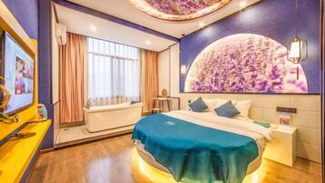 Una habitación de hotel moderna con una cama grande, una bañera y un mural en la pared.