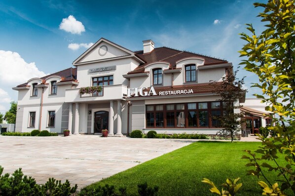 A two-story building with a large entrance and a sign for 'EIGA RESTAURACJA'.