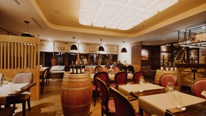 A restaurant interior with wooden tables, red chairs, and wine barrels. - Hotel Figa (Komorniki)