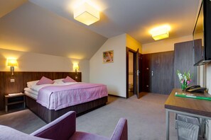 Una habitación de hotel con cama, lámparas de noche, un escritorio, una silla y un televisor.