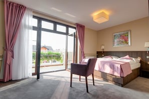 Una habitación de hotel con cama, una silla, un cuadro y vistas al exterior.
