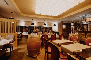 A restaurant interior with wooden tables, red chairs, and wine barrels.
