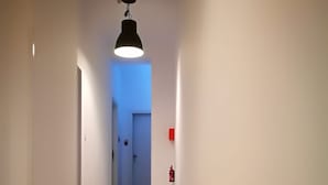 A hallway with a striped floor, a ceiling light, and a fire extinguisher on the wall. - Simply House in Bari 2 (Bari)