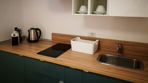 A modern kitchen with a stainless steel range hood, a built-in sink, and a countertop with a kettle and a coffee maker. - Simply House in Bari 2 (Bari)